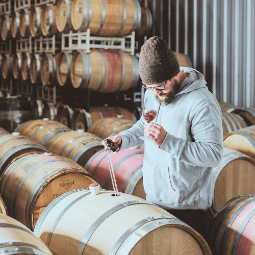 Man tasting wine in barrel room at Three Sisters Winery, Oregon.